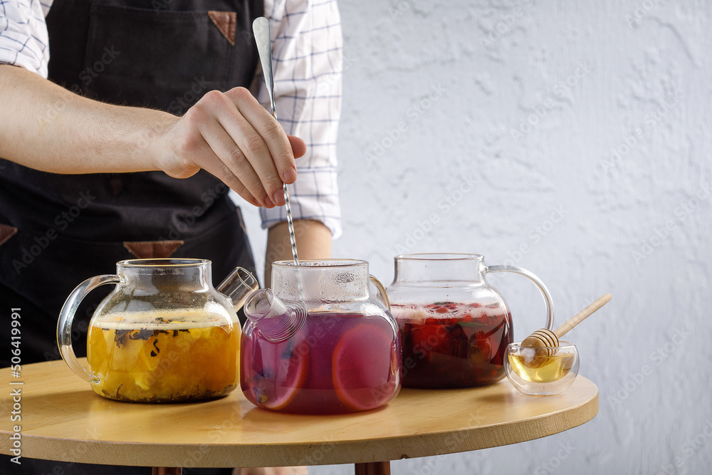 Barmen preparing tea in restaurant. Teapots on table in restaurant. Barmen's hands Barmen preparing tea in restaurant. Teapots on table in restaurant. Barmen's hands