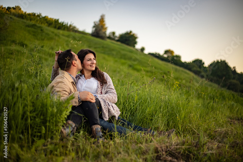 village couple in love gossiping gently peacefully, sitting facing each other man kissing girl in old-fashioned retro clothes