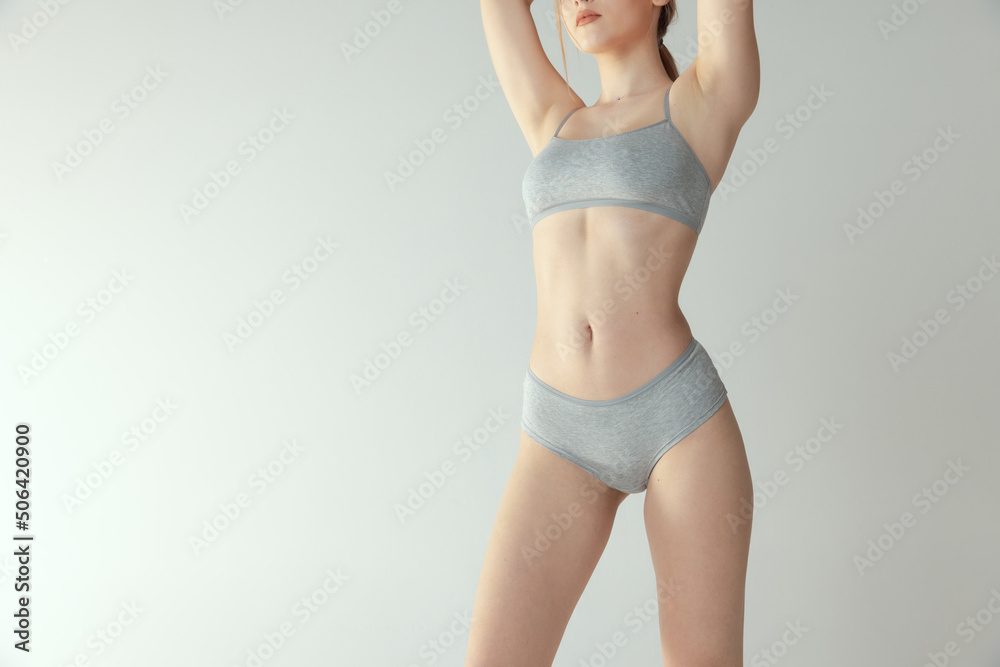Cropped portrait of slender, fit female body in cotton underwear isolated  over grey studio background. Following healthy lifestyle Stock Photo