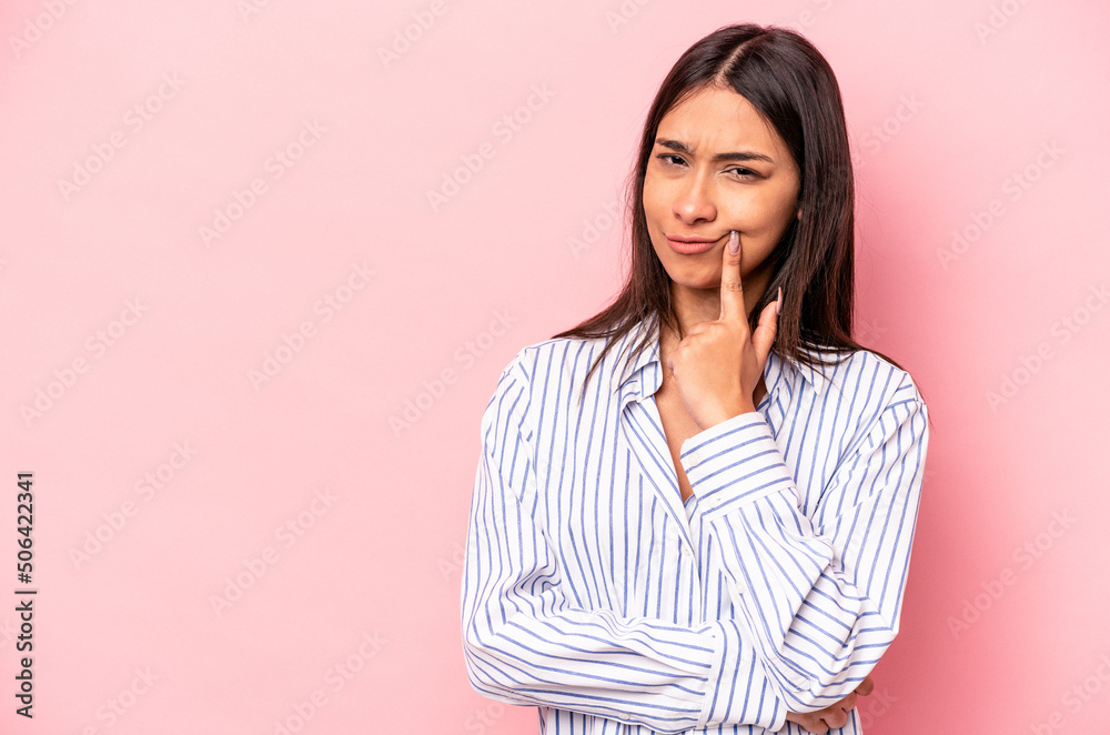 Young hispanic woman isolated on pink background looking sideways with doubtful and skeptical expression. Young hispanic woman isolated on pink background looking sideways with doubtful and skeptical expression.