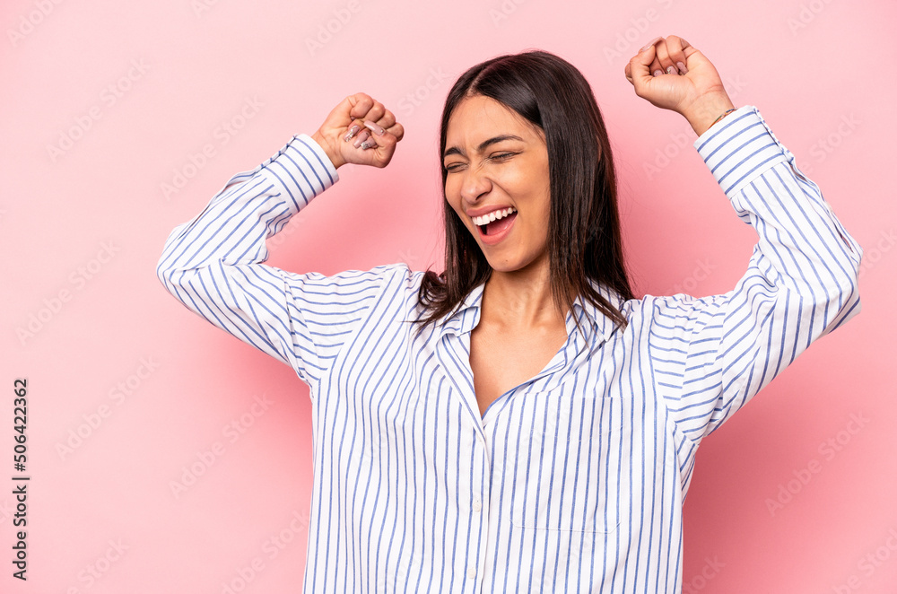 Young hispanic woman isolated on pink background raising fist after a victory, winner concept. Young hispanic woman isolated on pink background raising fist after a victory, winner concept.