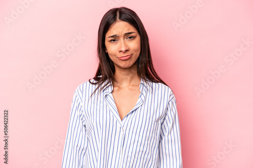Young hispanic woman isolated on pink background sad, serious face, feeling miserable and displeased.
