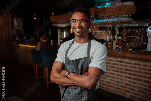 African American male standing in restaurant with crossed arms