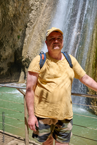 A man stands in front of a waterfall. Autumn water stream Ayun. River Nahal Ayun. Reserve and national park. Upper Galilee, Israel photo