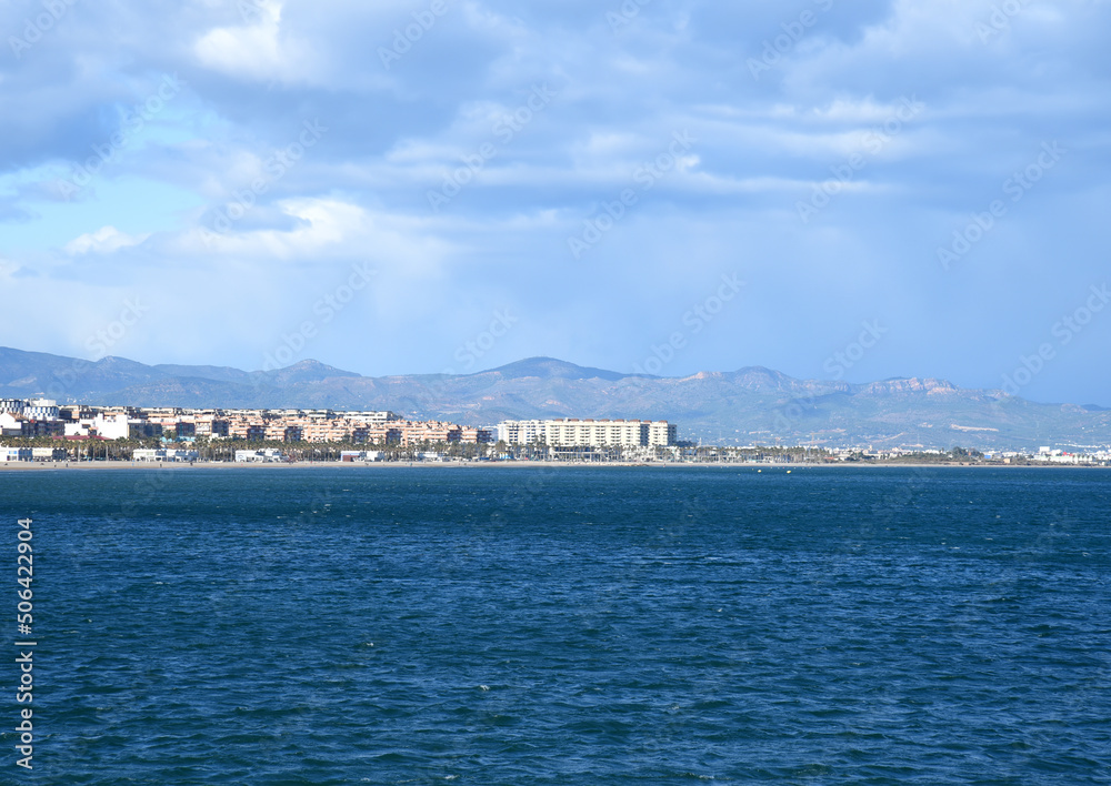 seascape of Mediterranean Sea. Coastline at Alboraya beach. View from sea to cityscape of Port Saplaya against the backdrop of the mountains. View blue seascape ocean. Coastal or coast view.