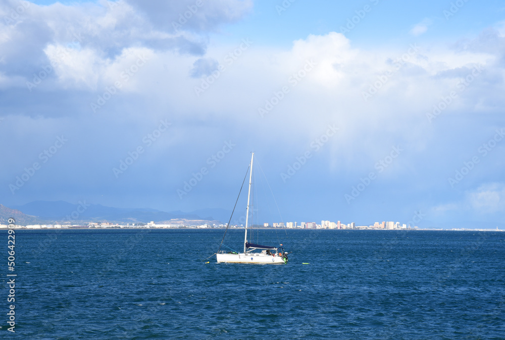 Yacht with a sail. Sailboat at sea on sailing on waves. Yachtsman during training on a sailboat. Skiff and Sailboat in sea near the Spanish coast. Sail sport in Yacht club. Sail boat on waves in sea.