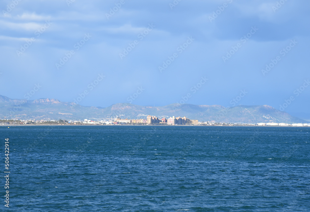 seascape of Mediterranean Sea. Coastline at Alboraya beach. View from sea to cityscape of Port Saplaya against the backdrop of the mountains. View blue seascape ocean. Coastal or coast view.