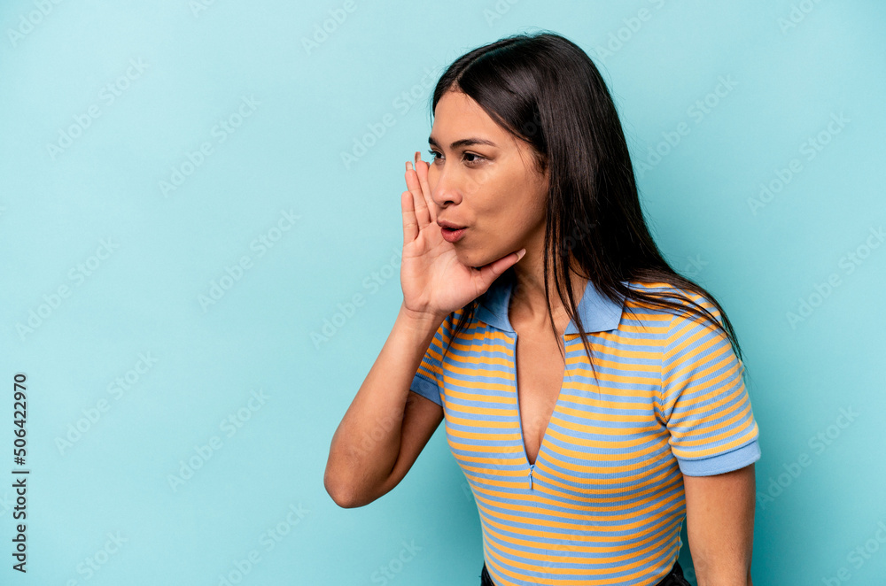 Young hispanic woman isolated on blue background is saying a secret hot braking news and looking aside Young hispanic woman isolated on blue background is saying a secret hot braking news and looking aside