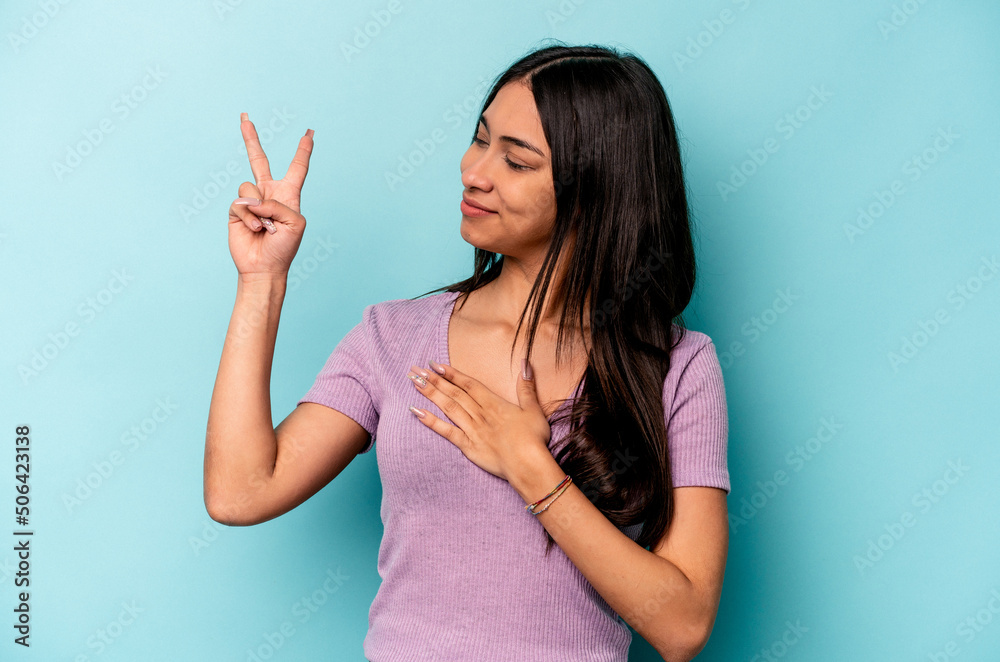 Young hispanic woman isolated on blue background taking an oath, putting hand on chest. Young hispanic woman isolated on blue background taking an oath, putting hand on chest.