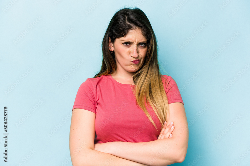 Fototapeta premium Young caucasian woman isolated on blue background frowning face in displeasure, keeps arms folded.