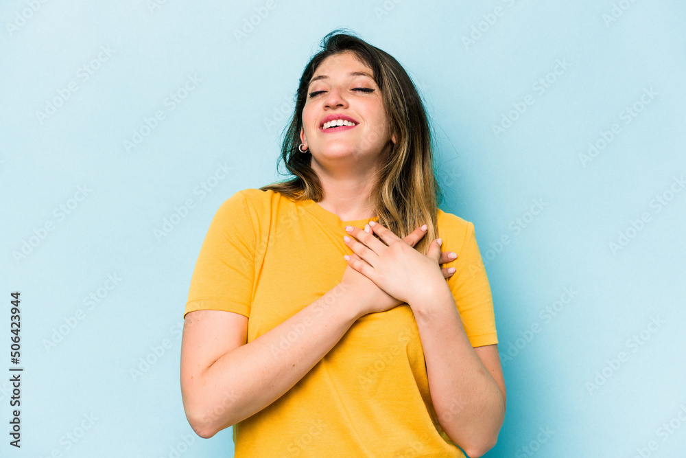 Fototapeta premium Young caucasian woman isolated on blue background has friendly expression, pressing palm to chest. Love concept.
