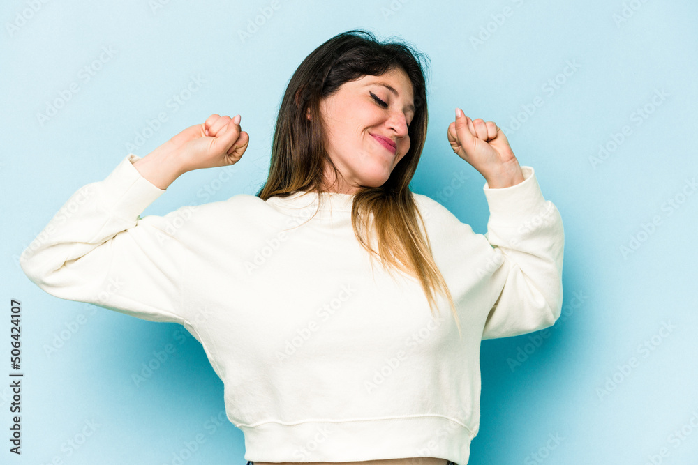 Fototapeta premium Young caucasian woman isolated on blue background stretching arms, relaxed position.