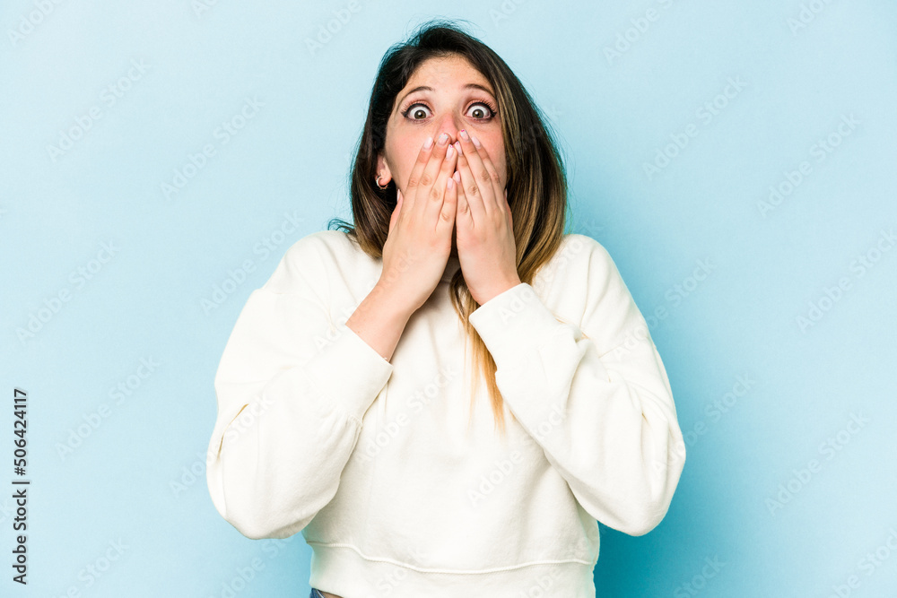 Young caucasian woman isolated on blue background shocked covering mouth with hands. Young caucasian woman isolated on blue background shocked covering mouth with hands.