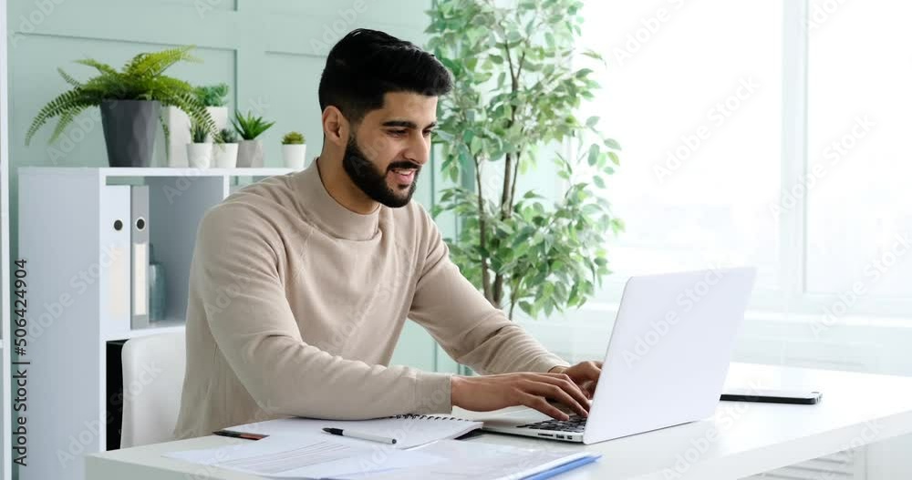 Smiling young businessman typing on laptop at office Smiling young businessman typing on laptop at office