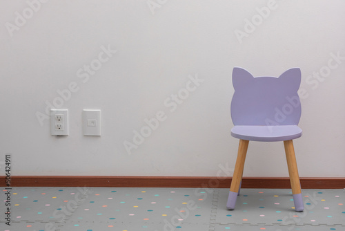 purple children's chair in an office with a white wall and contacts on the wall