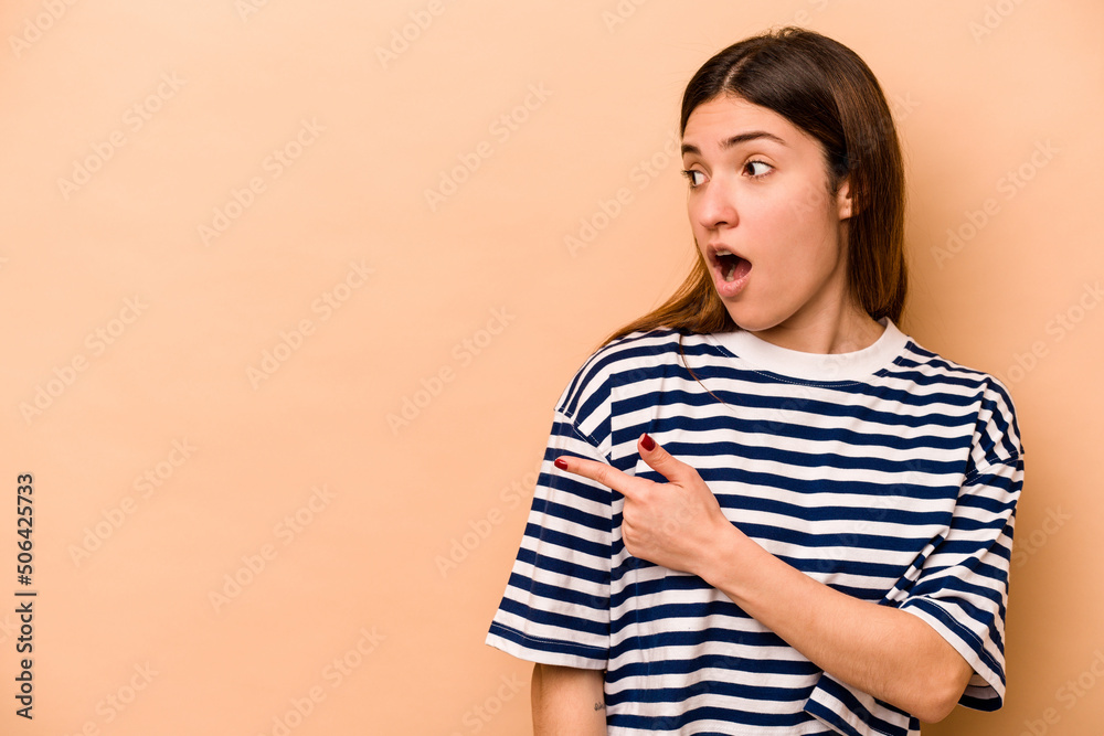 Young hispanic woman isolated on beige background points with thumb finger away, laughing and carefree. Young hispanic woman isolated on beige background points with thumb finger away, laughing and carefree.