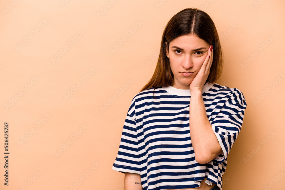 Young hispanic woman isolated on beige background who feels sad and pensive, looking at copy space. Young hispanic woman isolated on beige background who feels sad and pensive, looking at copy space.