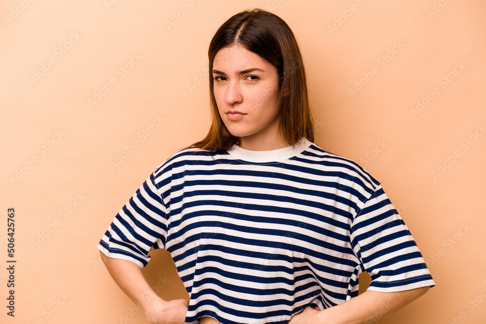 Young hispanic woman isolated on beige background frowning face in displeasure, keeps arms folded. Young hispanic woman isolated on beige background frowning face in displeasure, keeps arms folded.