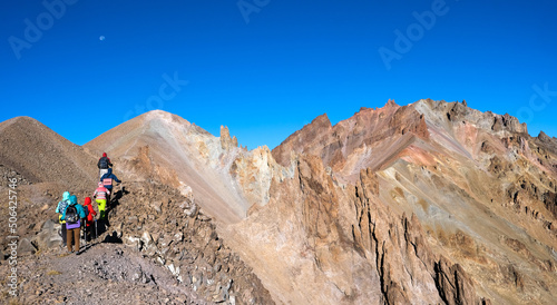 Group of hikers climbing stony mountains in daytime, panorama