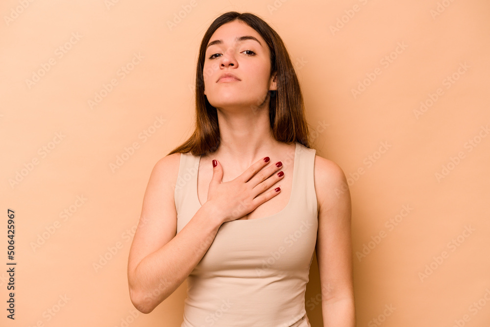 Young hispanic woman isolated on beige background taking an oath, putting hand on chest. Young hispanic woman isolated on beige background taking an oath, putting hand on chest.