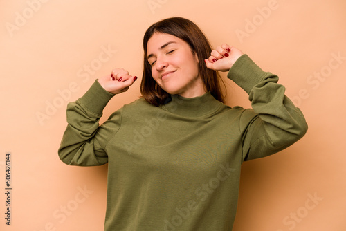 Young hispanic woman isolated on beige background stretching arms, relaxed position. © Asier