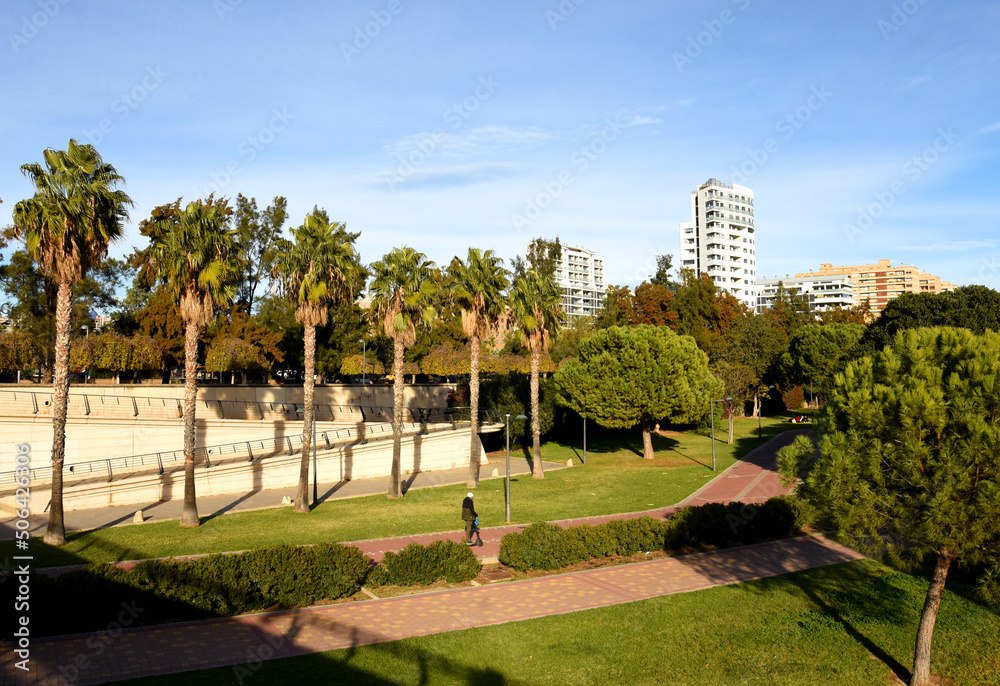 City park with gardens and palm trees in Valencia. Valencia Central Park on Turia River. Facade of a building. Residential buildings with windows and balconies. City architecture in central streets.