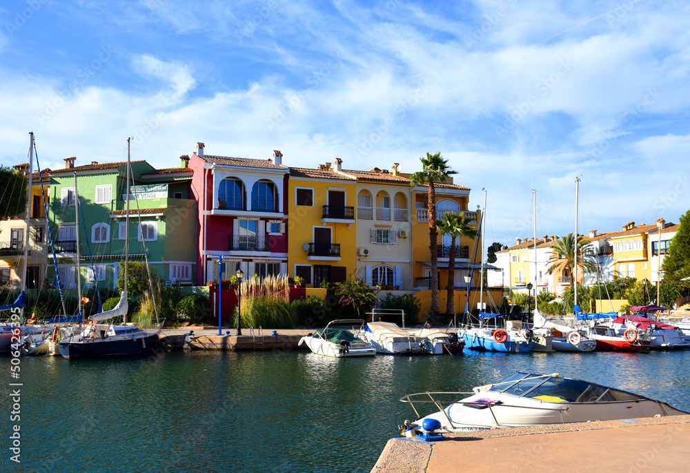 Jetty with yacht. Yachts and motor boats in marina Port Saplaya, Valencia. Yacht and fishing motorboat in yacht club. Colourful houses with apartments at coast Mediterranean Sea. Sailboat near pier.