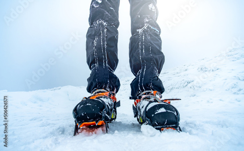 Man wearing crampons on trekking boots standing on snow