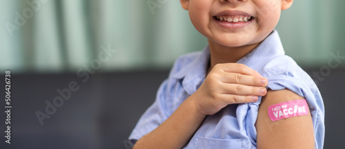 Foto Portrait of happy smile vaccinated little asian kid boy children ages 5 to 11 years old posing show arm with medical plaster after Injection vaccine Covid-19 protection