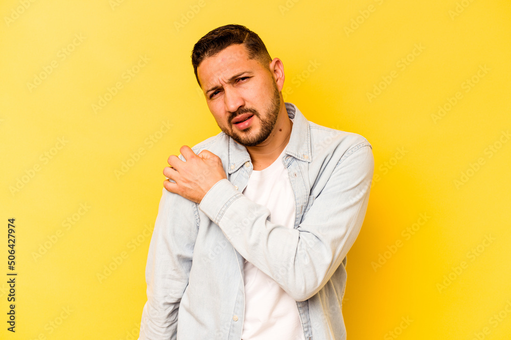 Young hispanic man isolated on yellow background having a shoulder pain. Young hispanic man isolated on yellow background having a shoulder pain.