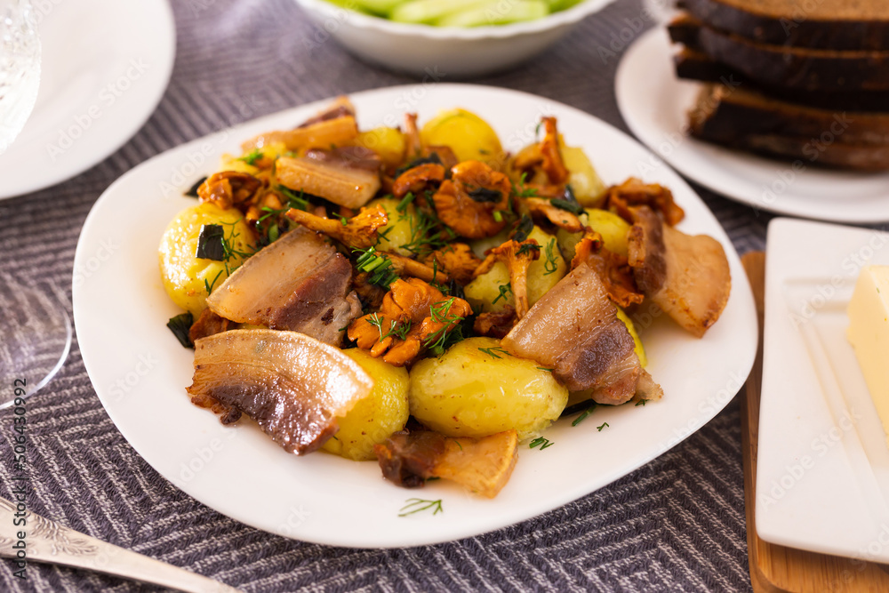 baked potatoes with chanterelles and bacon served with herbs on white plate baked potatoes with chanterelles and bacon served with herbs on white plate