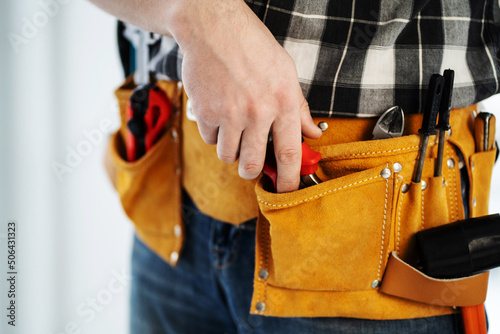 Tool kit in repairman's mounting belt hanging on hips during workday