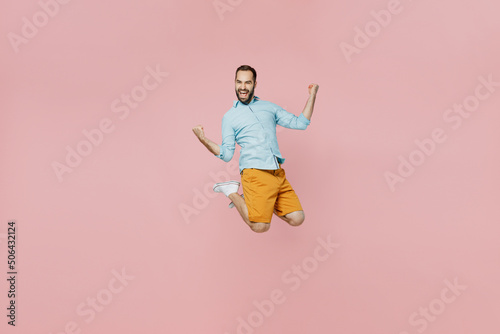 Full body young excited overjoyed caucasian happy man 20s wear classic blue shirt jump high do winner gesture isolated on plain pastel light pink background studio portrait. People lifestyle concept.