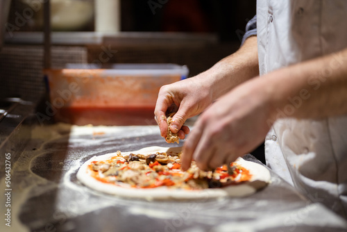 Pizza making process. Male chef hands making authentic pizza in the pizzeria kitchen. photo