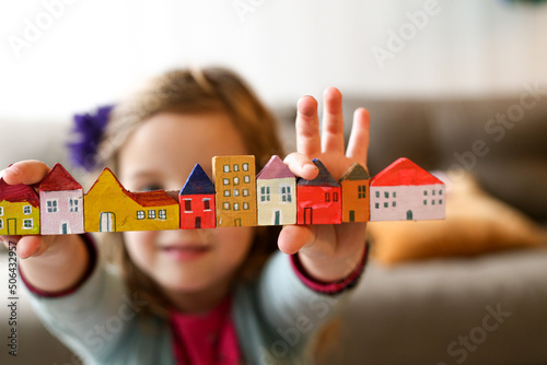 Housing affordability with a family concept shown with child holding blocks of coloured homes photo