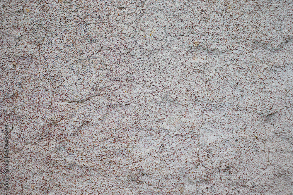An old concrete wall with remnants of gray paint crumbling from time. Texture of eroded concrete. An old concrete wall with remnants of gray paint crumbling from time. Texture of eroded concrete.