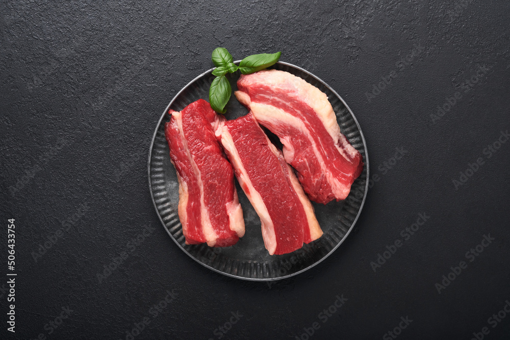 Steak beef. Raw steak New York with rosemary and spices on old iron plate on old dark stone background. Top view. Mock up.