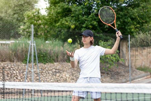Accurate portrait of a young boy playing tennis serving against his opponent in the middle of a tennis match © NOWRA photography