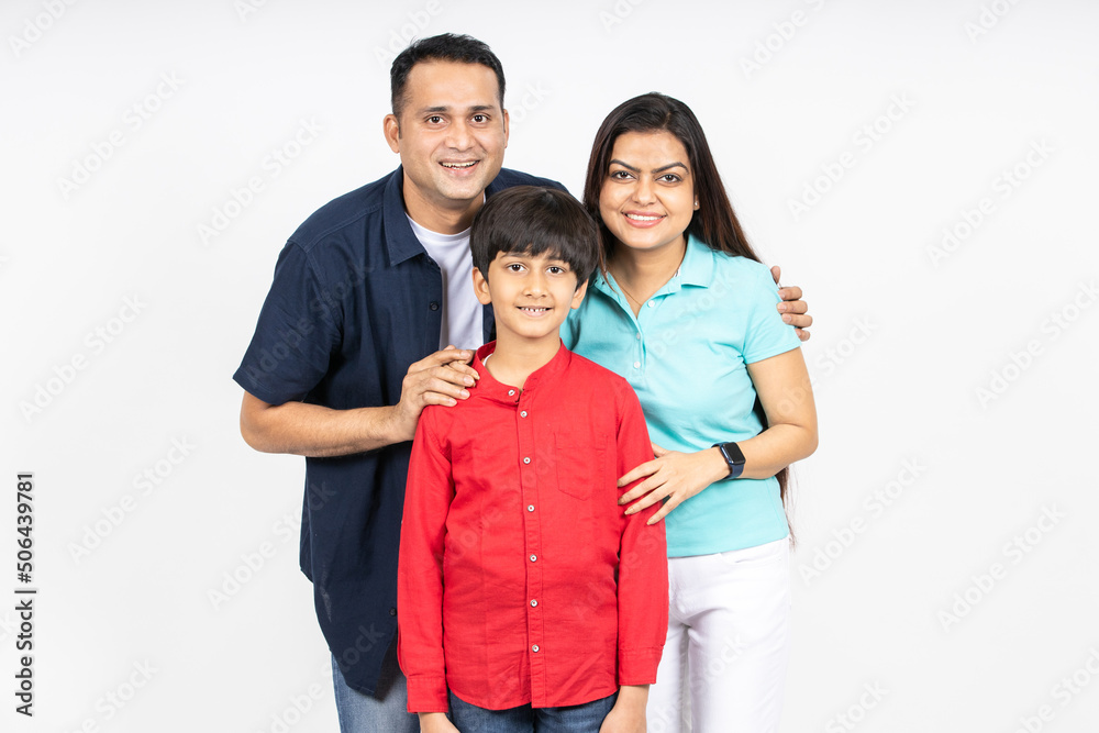 Happy young attractive indian family looking at camera isolated on white studio background. Smiling urban asian parents standing with little kid son. Happy young attractive indian family looking at camera isolated on white studio background. Smiling urban asian parents standing with little kid son.