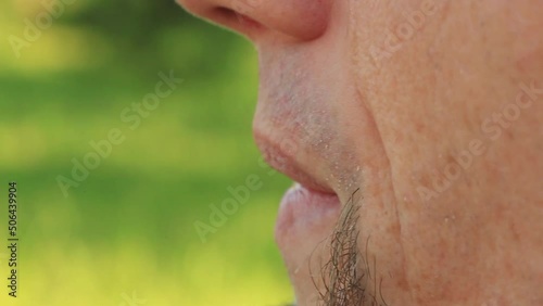 Portrait of young smoking man closeup outdoors. Close up video of adult smoker in summer park, unhealthy lifestyle