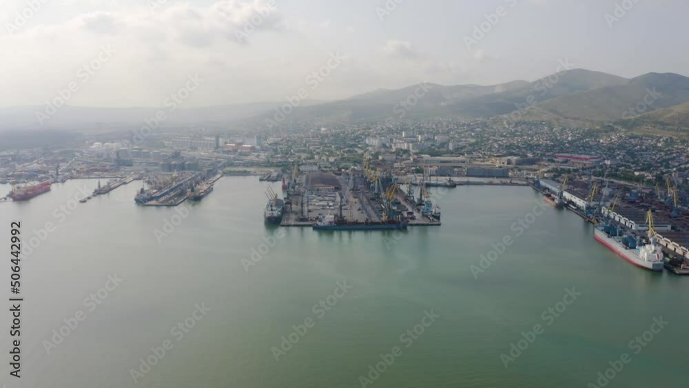 Industrial seaport Novorossiysk , top view. Port cranes and cargo ships and barges. Loading and shipment of cargo at the port. View of the sea cargo port with a bird's eye view. Industrial seaport Novorossiysk , top view. Port cranes and cargo ships and barges. Loading and shipment of cargo at the port. View of the sea cargo port with a bird's eye view.