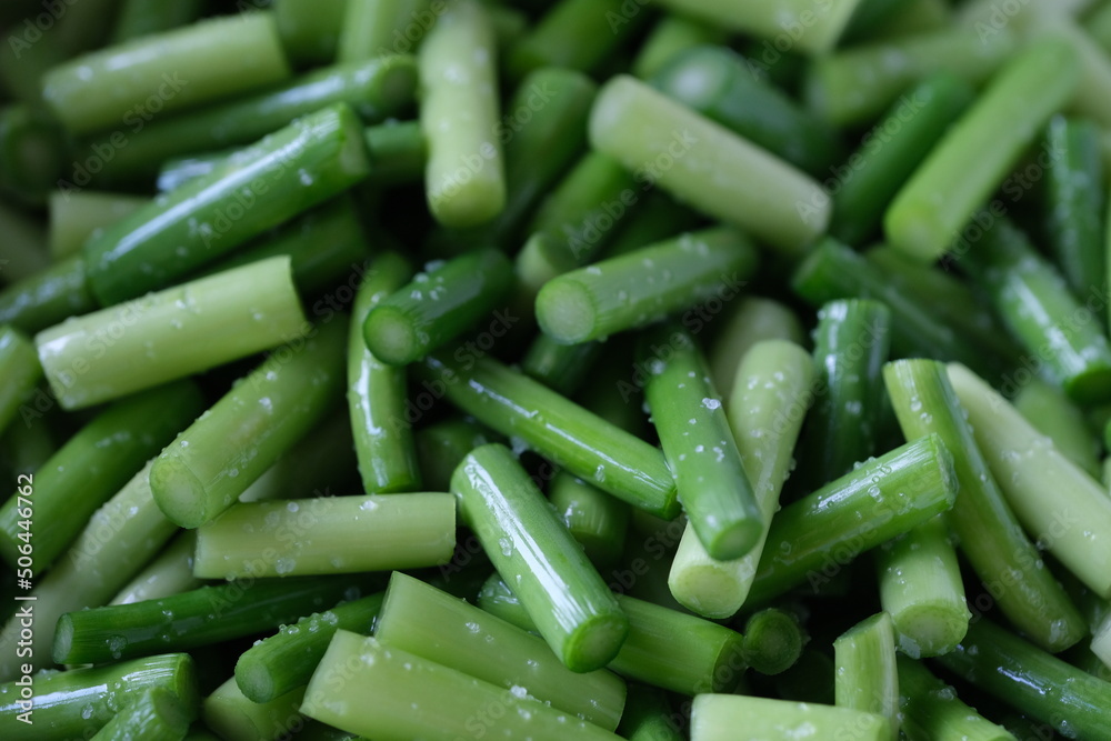 close up many chopped garlic shoot with salt. Salted green vegetable