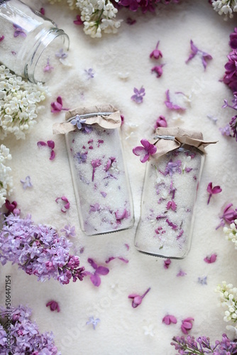 Sugar with lilacs in small glass jars on scattered sugar. Edible flowers in cooking and confectionery. Seasonal spring preparations. Lilacs of different varieties.