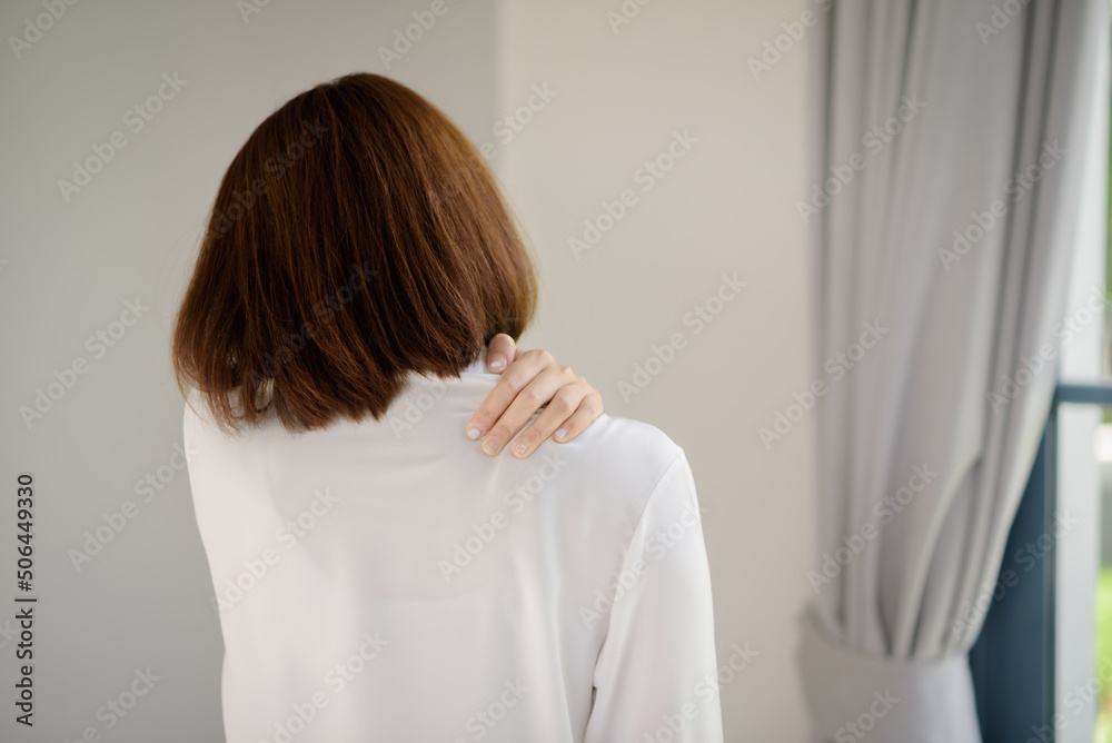 Rear view of an Asian woman with shoulder pain symptoms. Rear view of an Asian woman with shoulder pain symptoms.