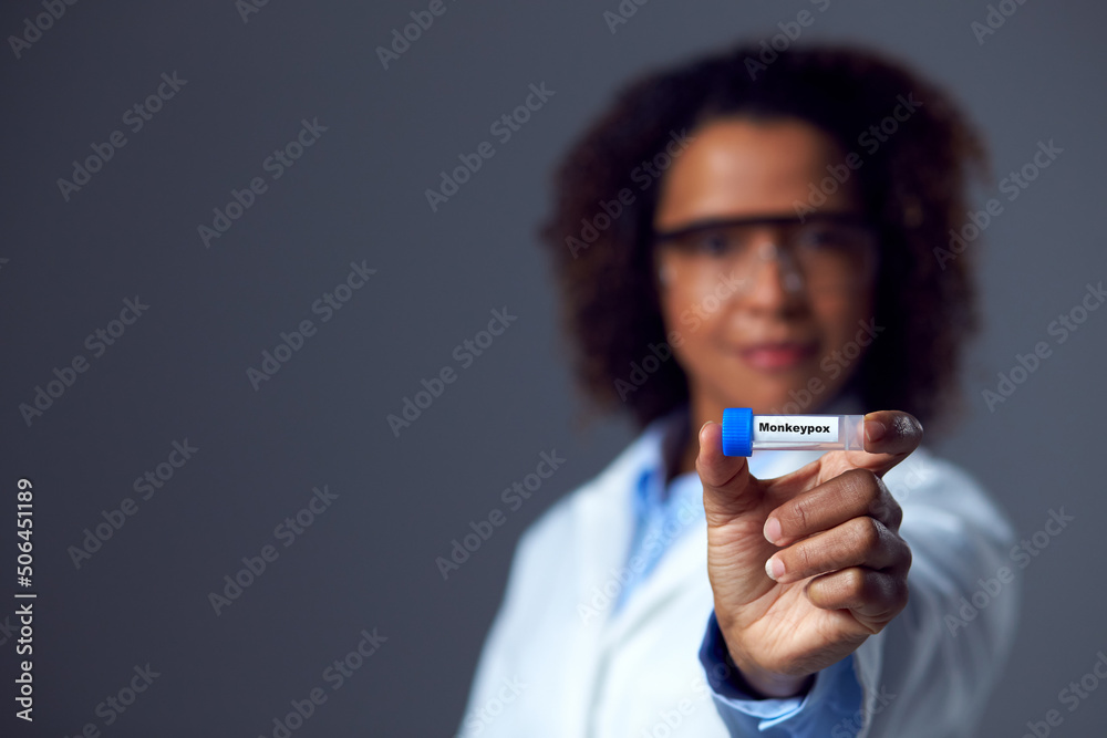 Studio Portrait of Female Lab Research Worker Wearing PPE Holding Test Tube Labelled Monkeypox Studio Portrait of Female Lab Research Worker Wearing PPE Holding Test Tube Labelled Monkeypox