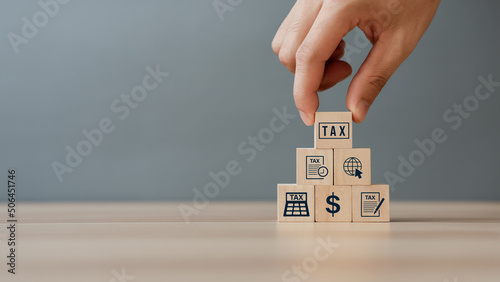 Hand putting tax icon in the wooden cube for income tax return and submit tax for payment tax documents online to the government photo