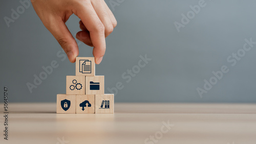 Hand putting document icon in the wooden cube for document management digital file data online records keeping, database technology, file access, and doc sharing.