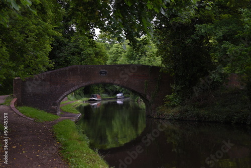 the arch bridge that goes over the canal in Stourton with a canal boat on the side of the canal photo