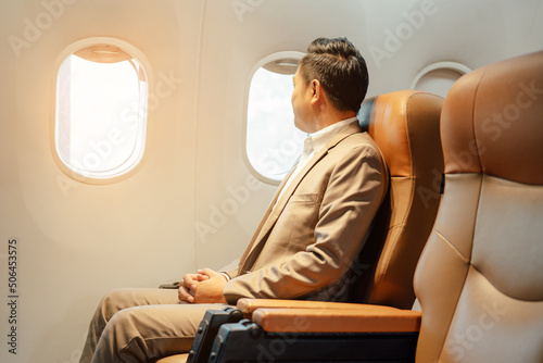 Fotografie Closeup businessman while sitting in airplane, Traveling and technology
