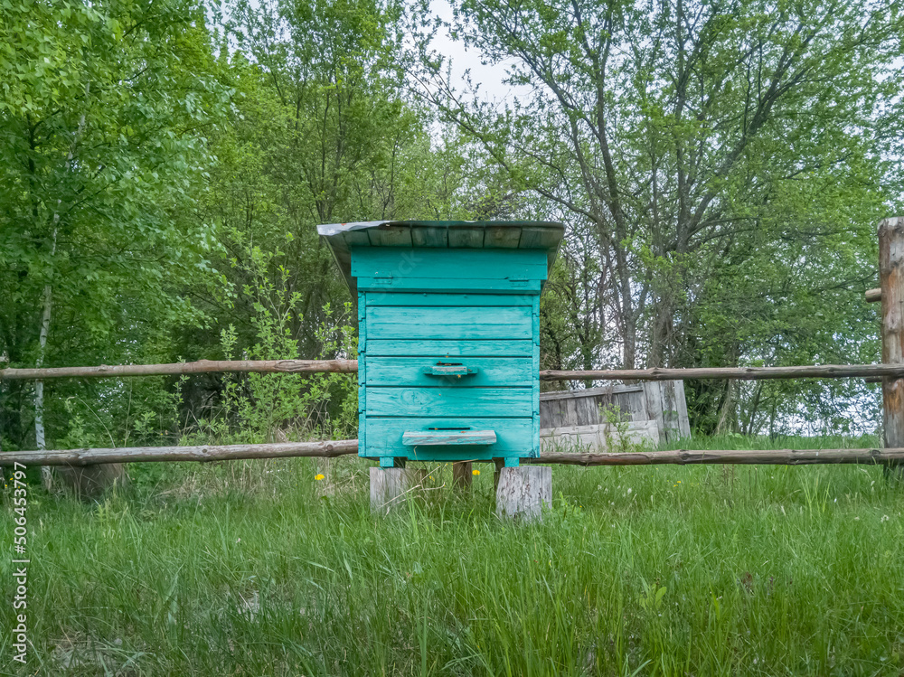 Old wooden turquoise beehive in a rural yard. Old wooden turquoise beehive in a rural yard.